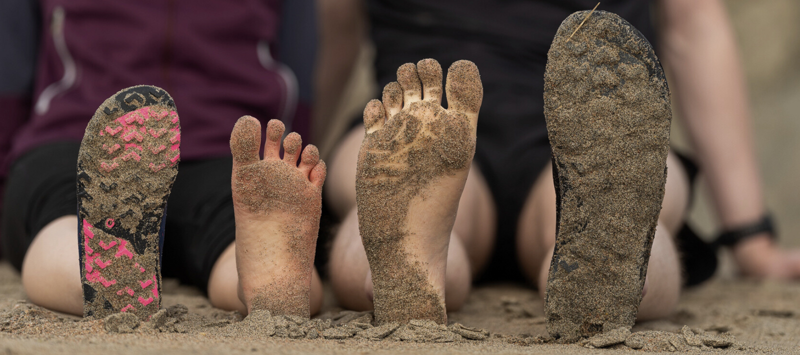 Barfotaskor med bred tåbox och fötter som är barfota i sanden