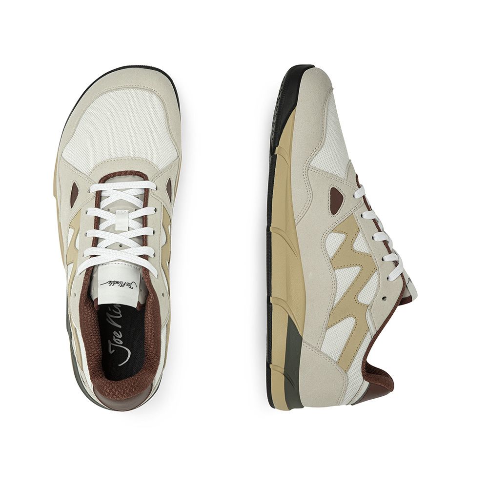 Joe Nimble Addict barfotasko i beige, brun och sandfärgad kombination. Sneakern har en bred tåbox, andningsbar ovandel i mesh och mockaliknande paneler, samt en lågprofilsdesign för naturlig fotrörelse. Synlig yttersula i beige och svart med lätt upphöjd häl.